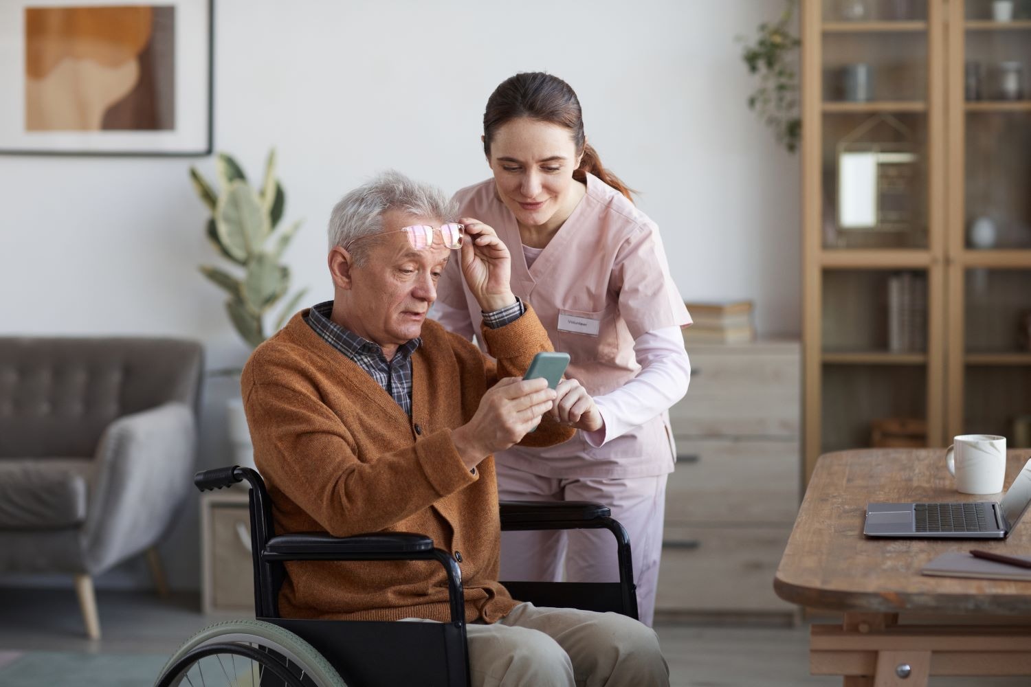 A support worker helping an older man use a mobile phone at home